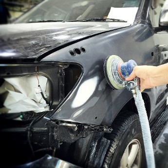 A person using a hose to polish a car, focusing on the vehicle's surface for a shiny finish