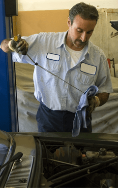 A man is repairing a car in a well-lit garage, surrounded by tools and automotive equipment